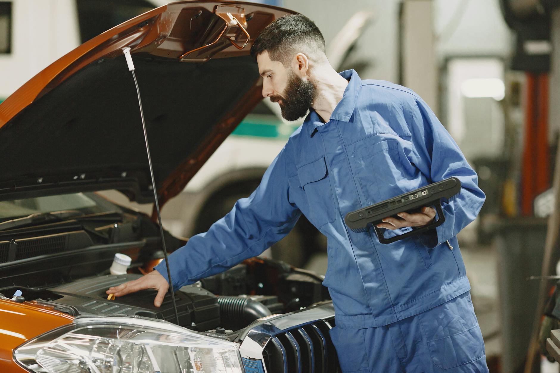 Mechanik w warsztacie ogląda silnik samochodu pod otwartą maską