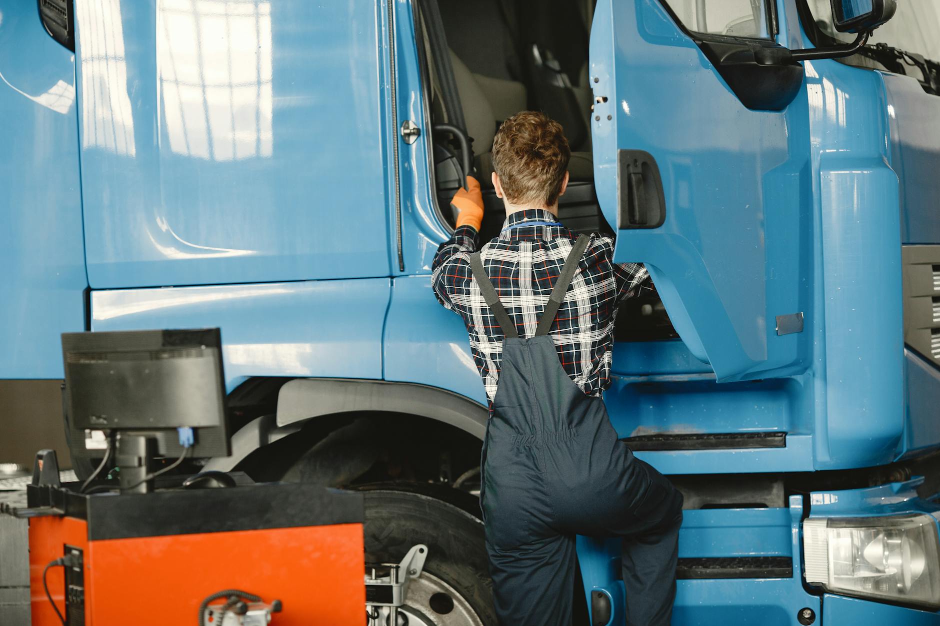 Mechanik w kombinezonie sprawdza ciężarówkę w oświetlonym warsztacie