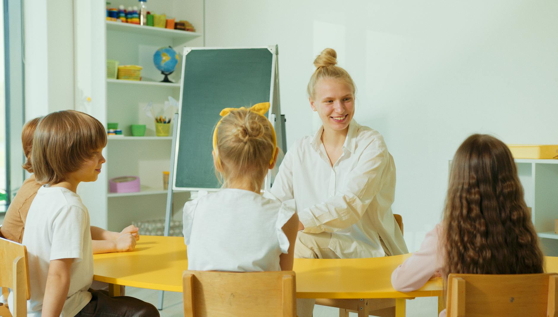 Nauczycielka rozmawia z przedszkolakami w kolorowej sali