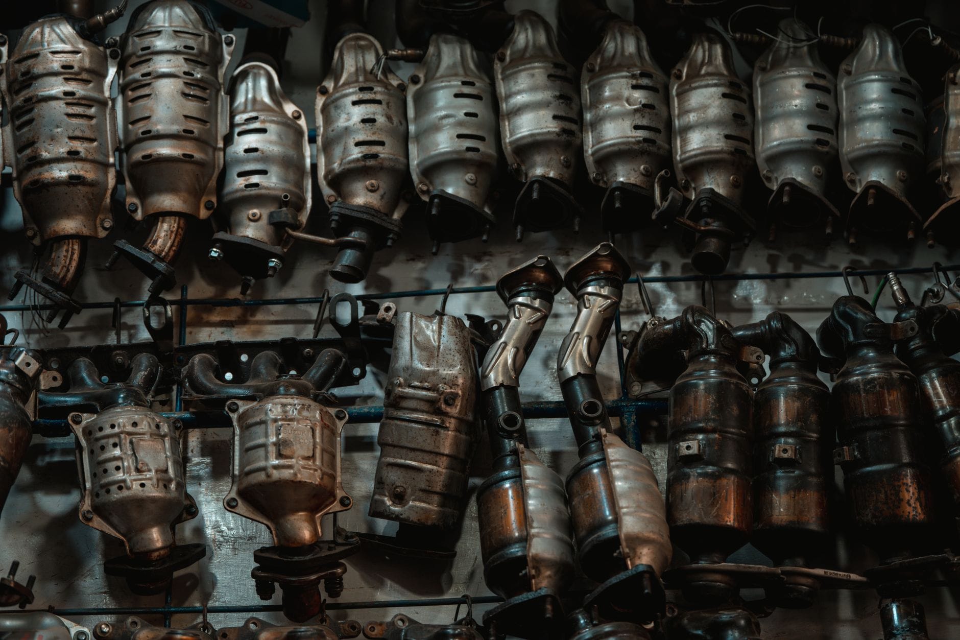Rzędy zużytych filtrów DPF i katalizatorów w warsztacie samochodowym