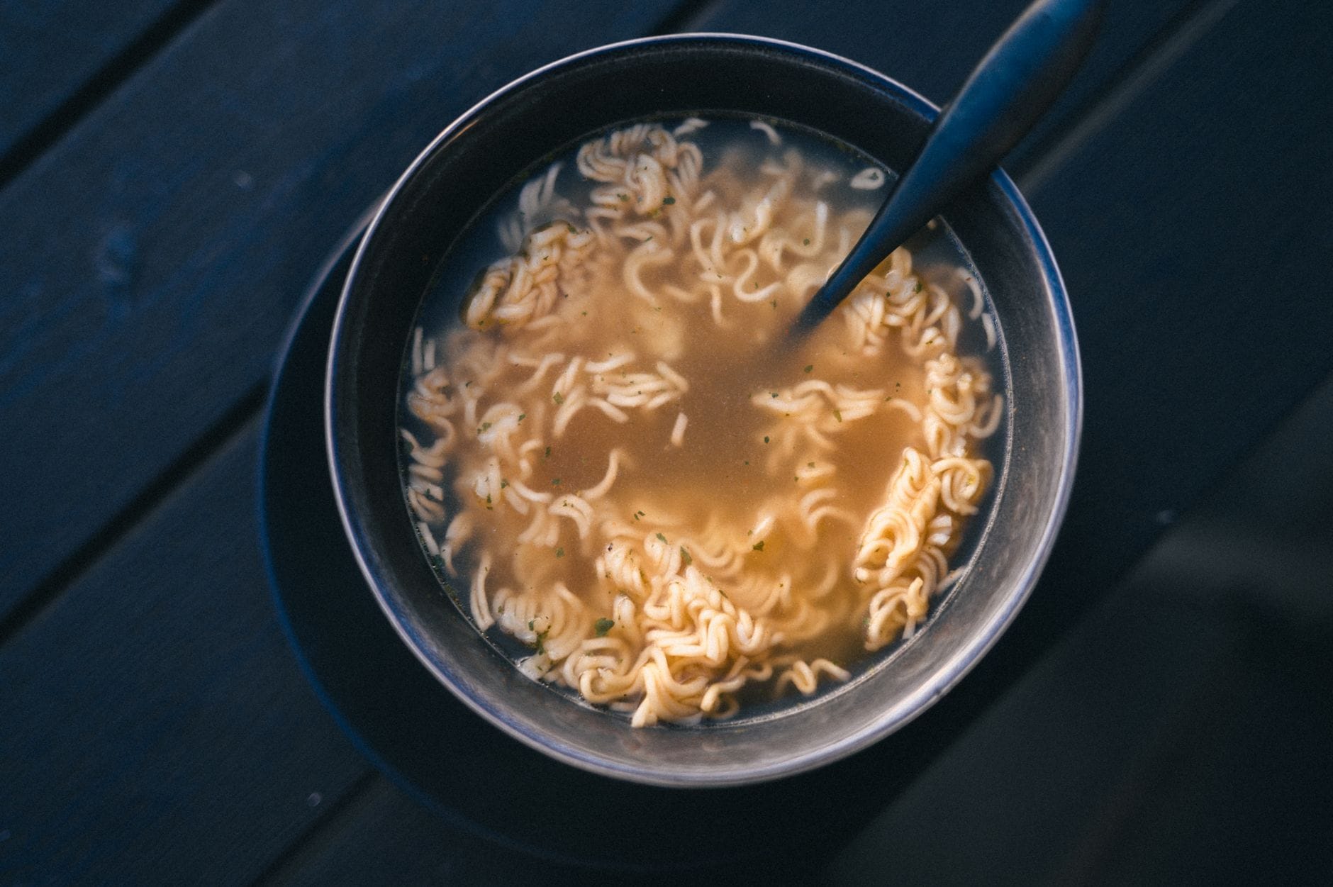 Zbliżenie na miskę gorącego ramen instant z bulionem na ciemnym tle