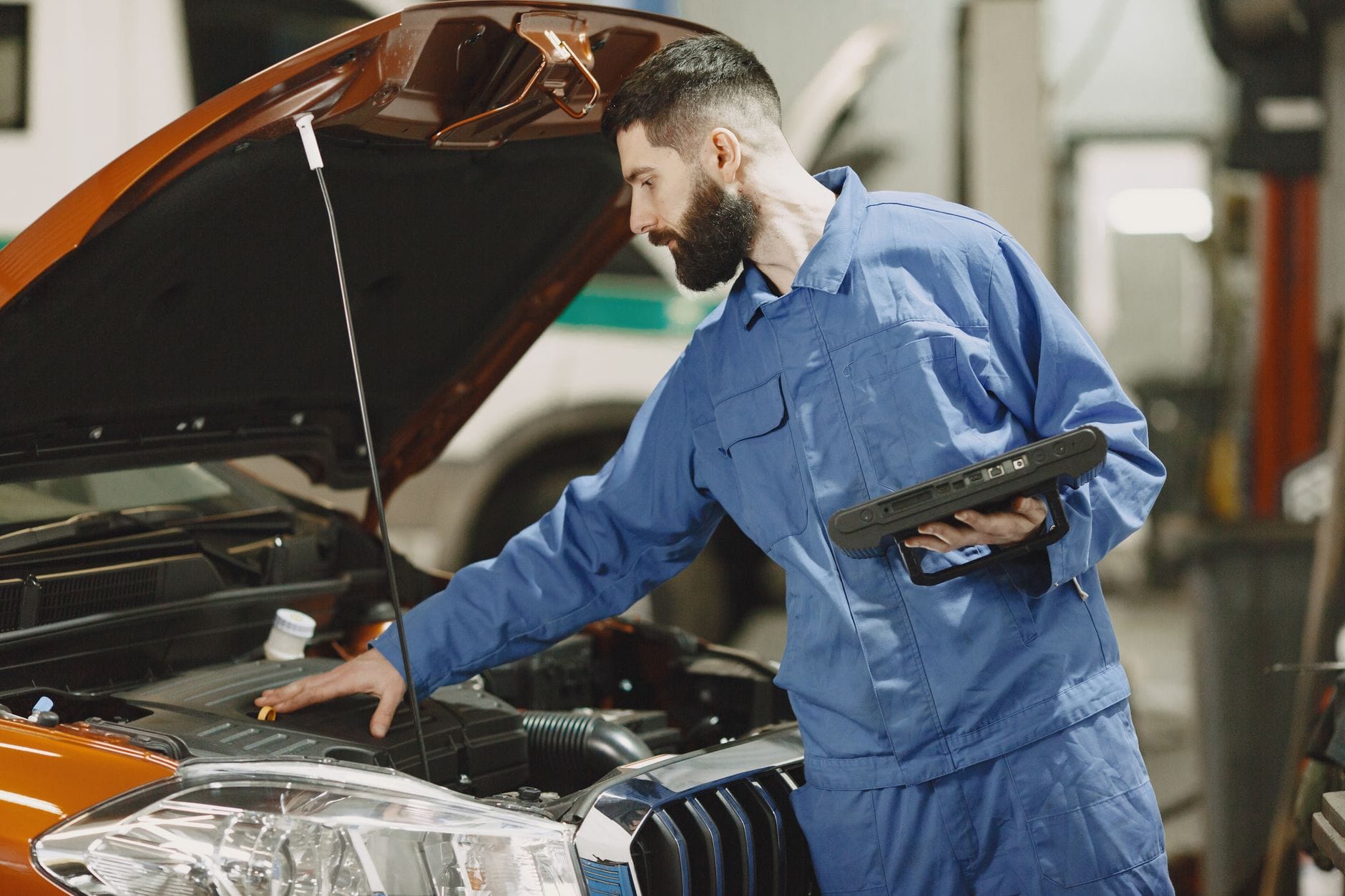 Mechanik w warsztacie sprawdza silnik samochodu pod otwartą maską
