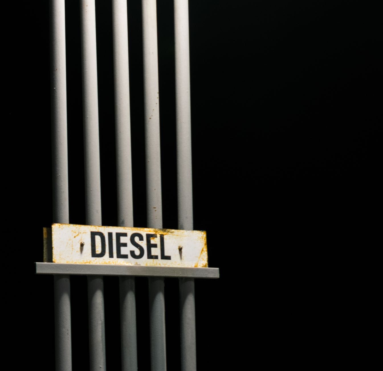Napis Diesel fuel na metalowych rurach na czarnym tle w nocy