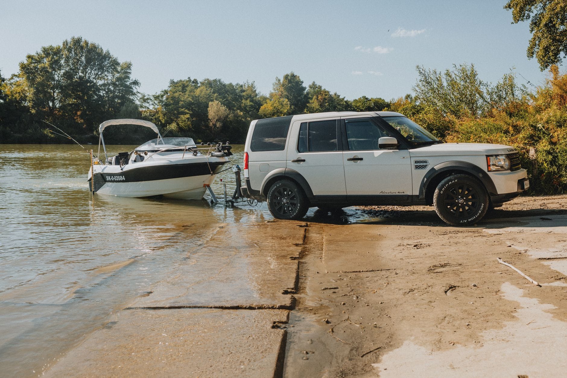 SUV z przyczepą wodującą motorówkę do rzeki w słoneczny dzień