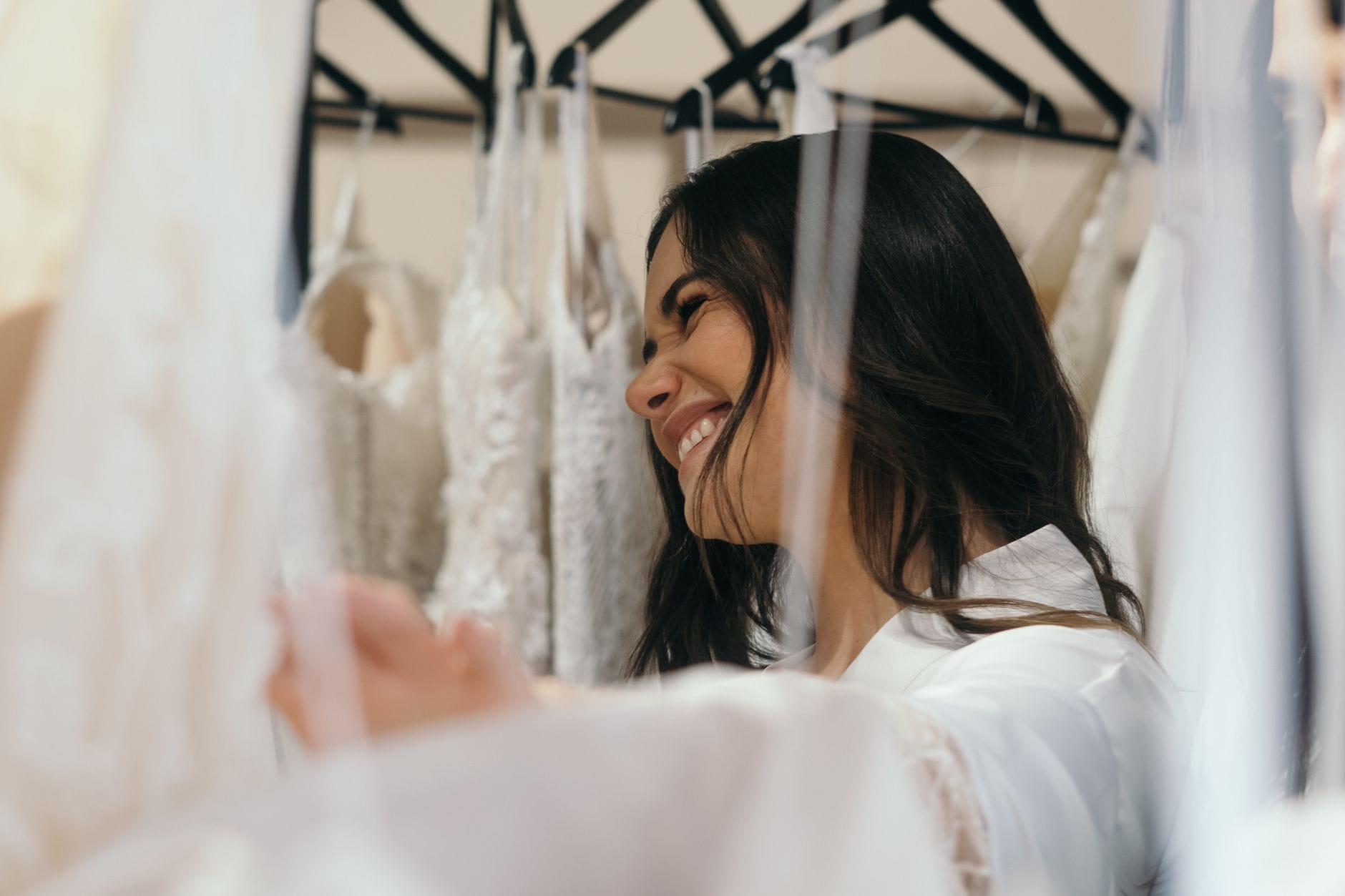 Uśmiechnięta panna młoda przymierza suknię ślubną w salonie bridal